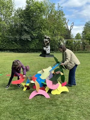 A woman and young girl making a sculptural shape by slotting together brightly coloured card pieces.