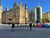 City square outside Leeds Train Station: a large tarmac pedestrian area with a zebra crossing over a cycle lane and a large stone building ahead.