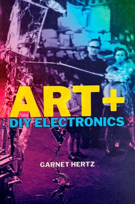 Cover of the book 'Art + DIY Electronics', showing two people looking at a makeshift robot, with a blue and purple filter applied.