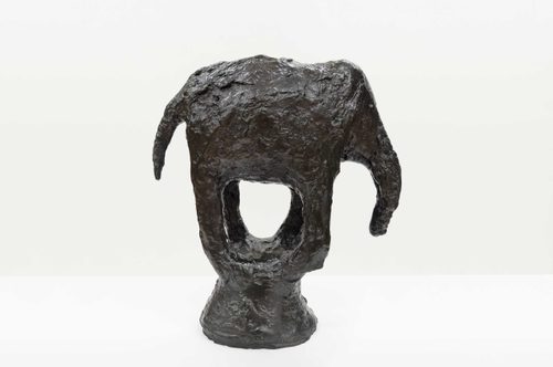 A dark, roughly textured sculpture of an abstract elephant with open spaces in its legs, which meet at the bottom to form a plinth.