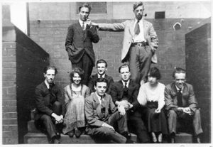 A black and white vintage photo showing a group of students from Leeds College of Art in 1920, they are grouped in front of a brick wall.