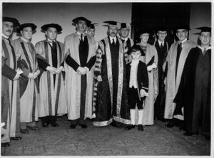 A graduation photo, showing a line of people in academic gowns and caps.