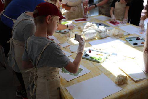 A young boy applying ink to an etching plate that he has made.