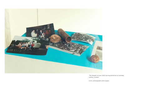 Several photos, melted or weathered copper coins and a short length of copper pipe are displayed on a plinth, the top of which has been painted blue.