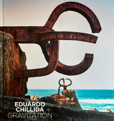 Cover of the book 'Eduardo Chillida: Gravitation', showing curved, rusted metal sculptures by a stony beach.