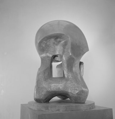 An abstract bronze sculpture, photographed in a studio. The top is smooth, curved and highly polished, while the lower parts and rougher, with scratches and gouges still evident where tools have been used.
