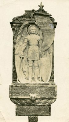 Relief sculpture of a standing, armoured angel, who holds a sword in one hand and a battle flag in the other, which reads 'From Strength to Strength'.