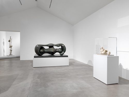 A white-walled gallery spaces holding three sculptures by Henry Moore.