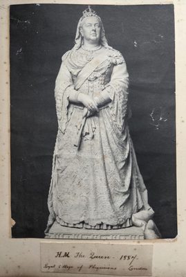 Black and white photo of a sculpture of a Queen Victoria, standing in a regal pose.