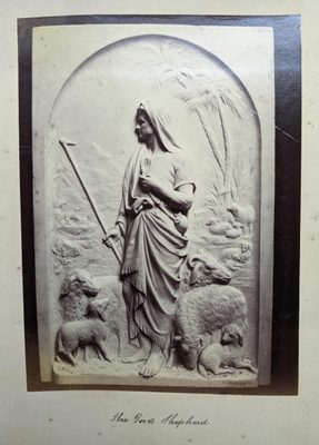 Black and white photo of a relief sculpture of a shepherd surrounded by sheep.