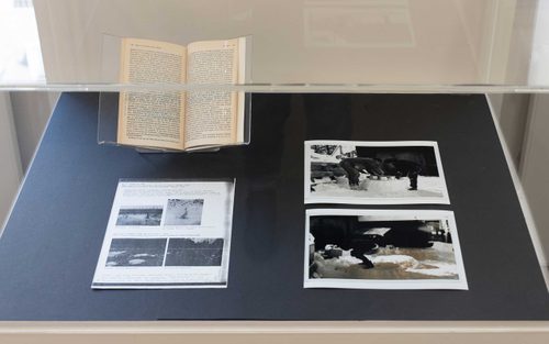 Display case with an open book, two photos taken in the snow, and a photocopied page.