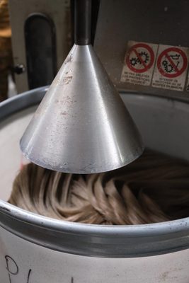 Flax fibres being processed into yarn inside a machine with a large conical apparatus.