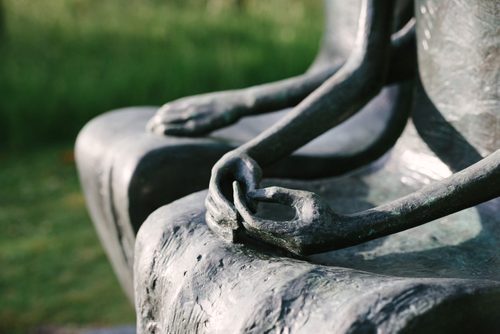 A close up showing the hands of Henry Moore's bronze sculpture King and Queen. The Queen's hands rest, lightly clasped, in her lap.