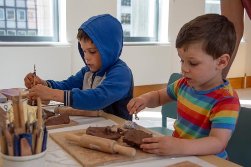 Two young boys sat at a table sculpting with clay.