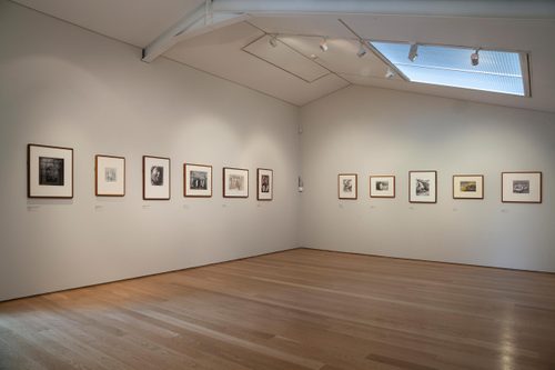 A gallery with white walls, high ceiling and wooden floor, with several framed drawings by Henry Moore hung on the walls.