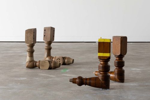 Two sets of two table legs, which have been cut at a 45 degree angle and reattached, to give them the appearance of kneeling.