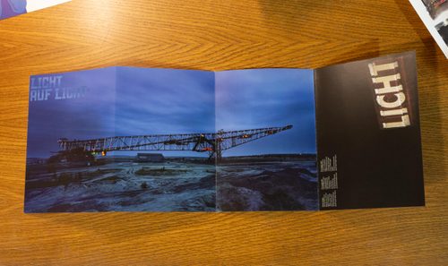 Promotional flyer for 'Licht auf Licht. It features a photo of industrial equipment, taken at twilight, lit up with coloured lights.