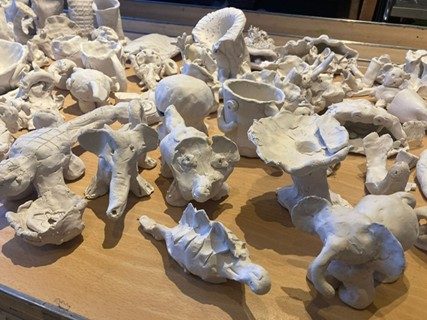 A table packed with small, unfired clay sculptures.