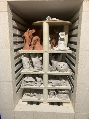 A kiln packed with small, unfired clay sculptures, spread over four levels.