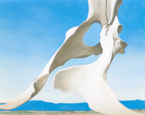 Painting by Georgia O'Keefe of an animal's pelvic bone. It has been painted from an angle that makes it appears massive against the landscape behind it.