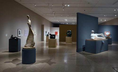 Wide shot of a gallery space containing numerous sculptures by Henry Moore and paintings by Georgia O'Keefe.