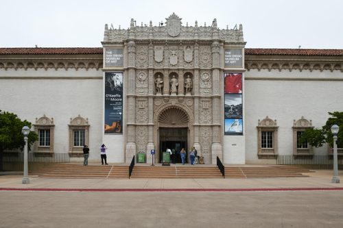 The entrance to The San Diego Museum of Art, with ornate stonework rising three storeys high, featuring decorative pillars, figurative sculpture and coats of arms.