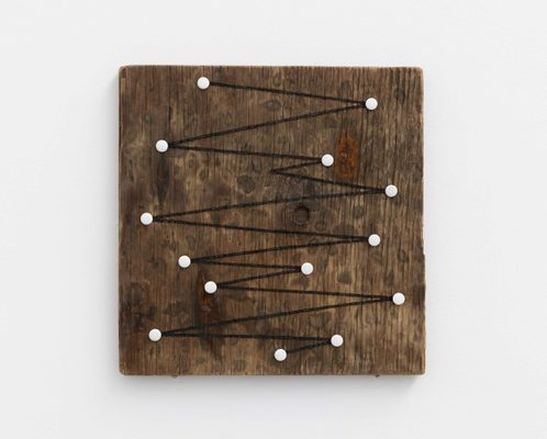 A square piece of dark wood with white drawing pins. A black line connects the pins in a zig-zag fashion. It has been burned into the wood using a magnifying glass and the sun.