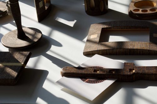 A collection of wooden objects that have all been 'decorated' with different patterns of black lines, burnt by the sun.