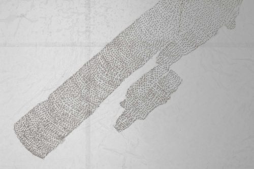 A translucent artwork made from waxed paper, pierced with hundreds of tiny holes that make up what could be the outline of a landmass or geological feature.