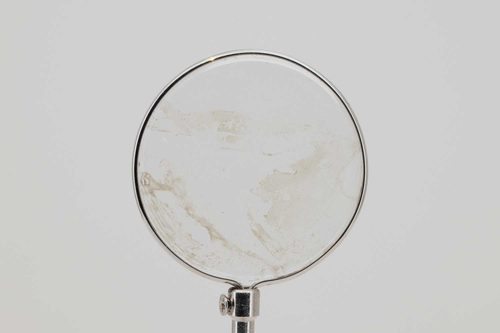 A tiny, transparent drawing of a mountain on the glass of a watch face in a circular frame.