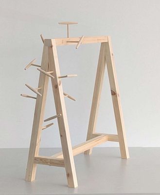 Wooden A-frame with several wooden corkscrew-like objects haphazardly stuck in one side.