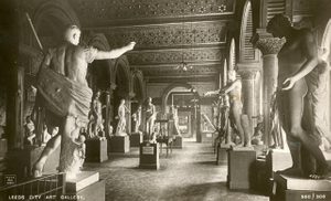 Black and white photo showing dozens of classical figurative sculptures, each stood on their own plinth. The room is large and open, with tiled walls and an elaborate tiled ceiling supported on many pillars.